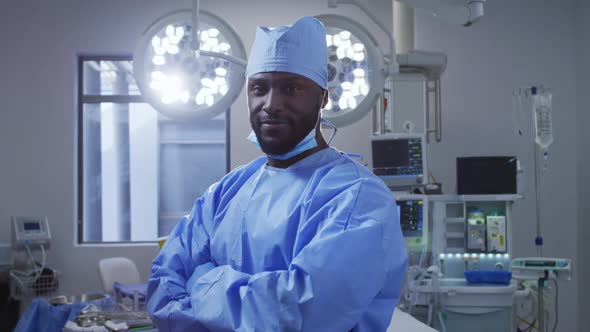 Portrait of african american male surgeon wearing protective clothes standing in operating theatre