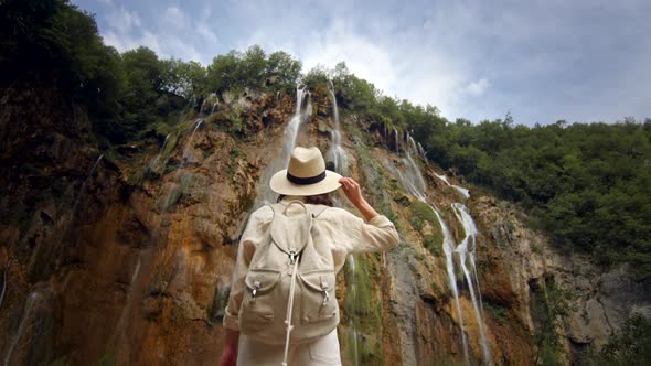 Attractive girl at the cascade of the waterfall on the mountain