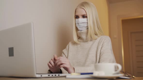 Businesswoman Working on a Laptop in a Cafe in a Medical Mask Removes