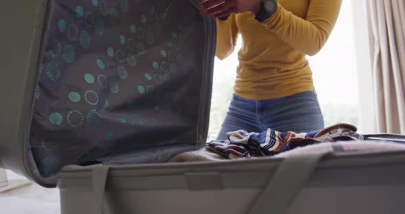 Midsection of biracial couple clapping hand with joy after packing suitcase for travel