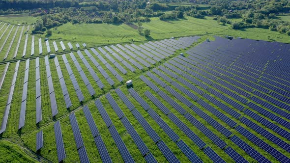 Aerial view on Solar Power Station in Green Field near River at Sunny Day