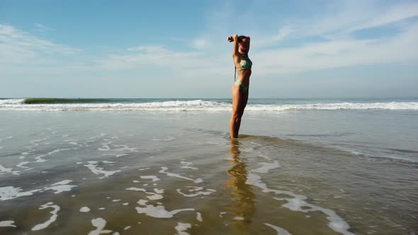 Fit tanned beauty posing on sandy Vietnam ocean coastline, orbit view