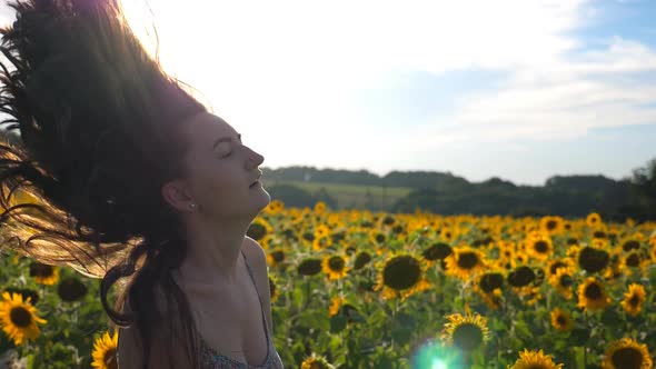 Close Up of Attractive Woman Rising Head and Waving Her Hair in Air with Beautiful Sunflower Field