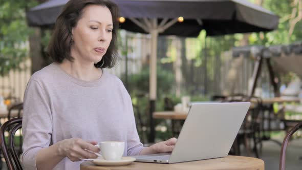 Outdoor Old Woman Drinking Coffee and Working on Laptop