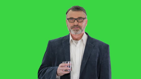 Handsome Bearded Senior Man in Business Suit Sipping Whiskey on a Green Screen Chroma Key