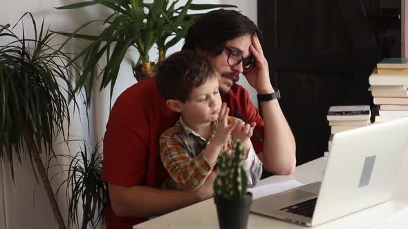 Tired father with a son at working place in home office