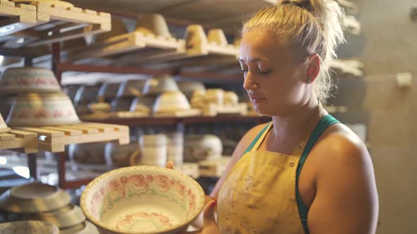 Woman Potter Artist Taking Big Clay Bowls Off of Wooden Rack in Pottery Workshop