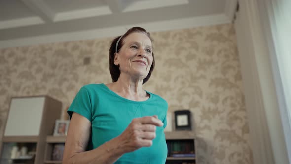 Happy Elderly Woman Running on a Treadmill at Home