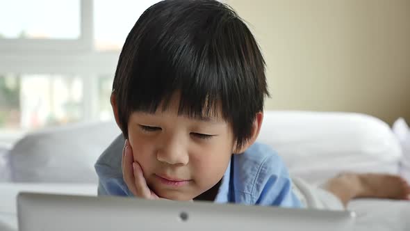 Cute Asian Boy Lying In Bed And Using Laptop On White Bed Slow Motion