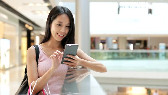 Woman use of mobile phone and carrying paper bags