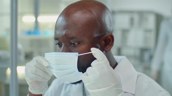 African American Scientist Putting on Mask and Glasses in Lab