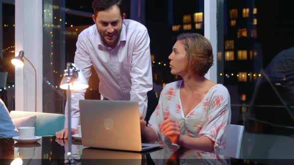 Business executives discussing over laptop