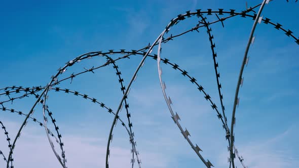 The Fence with Barbed Wire on the Background of a Gloomy Cloudy Dark Blue Sky