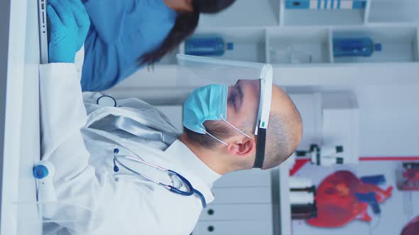 Vertical Video: Doctor Typing the Treatment on Laptop