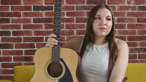 Young Joyful Woman with Smile Leans on an Acoustic Guitar and Looks Straight Front View
