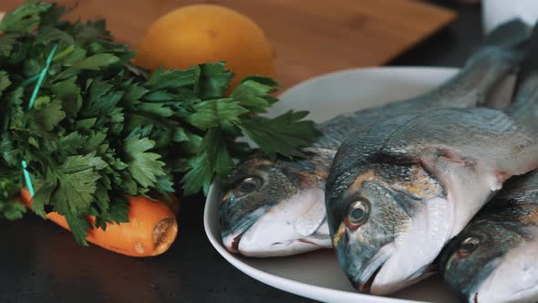 Fresh Fish Is Placed On A White Plate With Lettuce Carrot and Lemon On The Side