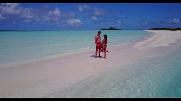 Boy and girl engaged on perfect coast beach holiday by blue green ocean with white sand background o