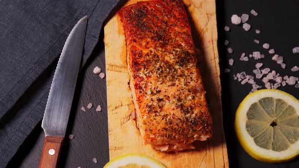 Delicious Baked Golden Salmon on a Black Plate in the Kitchen