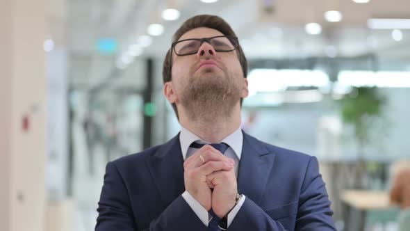 Portrait of Hopeful Young Businessman Praying Forgiveness