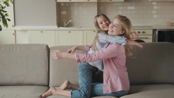 People and Family Concept  Happy Smiling Girl with Mother Hugging on Sofa at Home