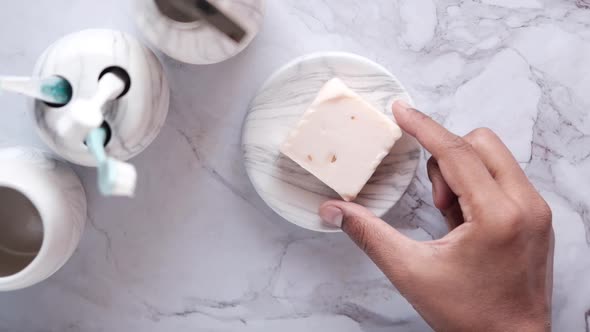 Hand Pick Homemade Natural Soap Bar on Tiles Background