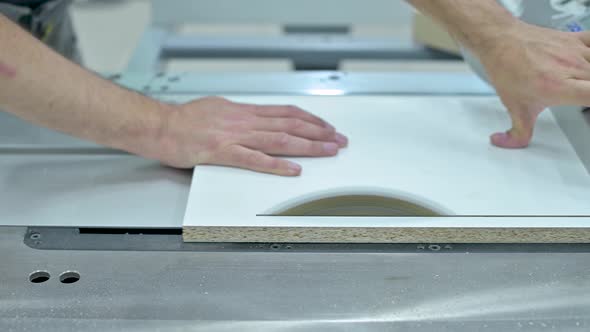 A man cuts off part of a wooden blank on a circular saw, not observing safety precautions