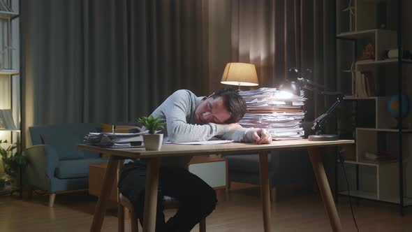 Tired Asian Man Sleeping Due To Working Hard With Documents At Home