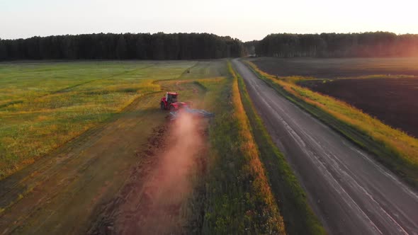 Red tractor with plow goes around obstacles