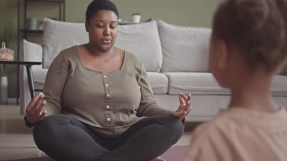 Black Woman Teaching Little Girl Meditation