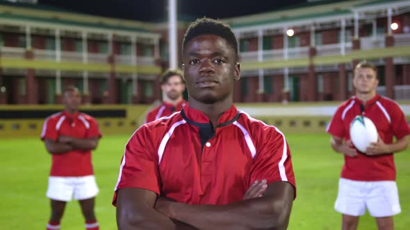 Male rugby players with rugby ball and arms crossed standing in stadium 4k