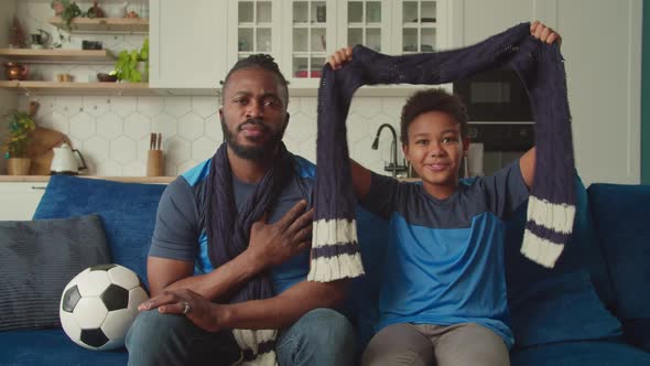 African Family with Son Watching Soccer Match on Tv and Singing National Anthem