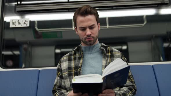 Handheld Focused Man Rides the Subway and Reads a Book a Student Goes to Study at the University