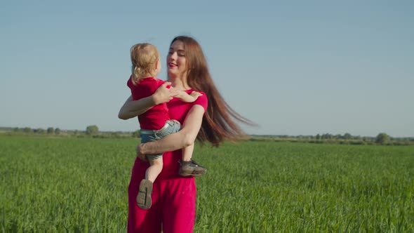 Cheerful Mother Tossing Up Child on Wheat Field