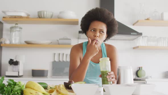 Happy african american woman preparing healthy drink in kitchen