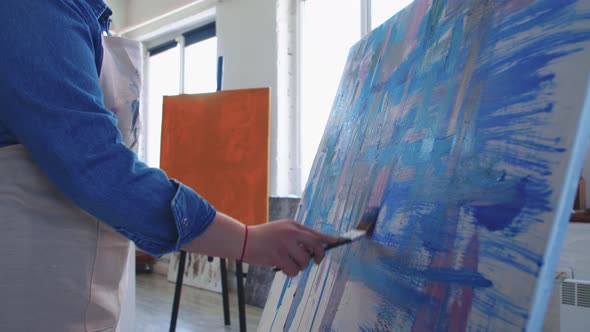 A Chubby Woman Paint Artist Drawing an Abstract Blue Painting with a Brush