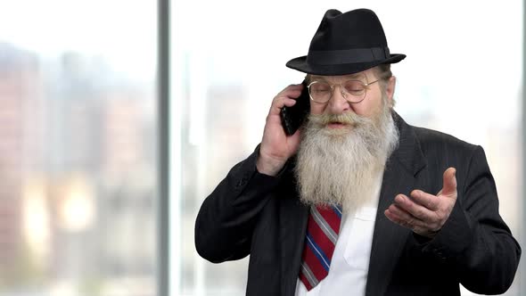 Bearded Senior Businessman Negotiating on Mobile Phone.