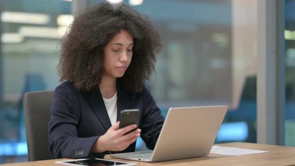 African Businesswoman with Laptop Using Smartphone