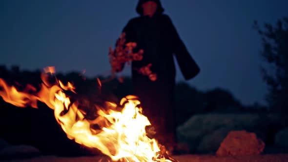 Scary witch conjures around the fire. 