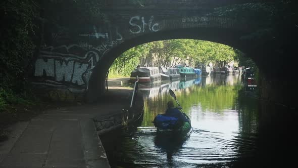Kayaking in urban setting through calm canals and under bridge in city of London
