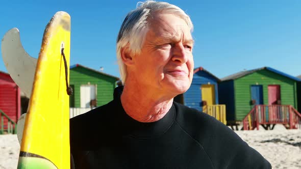 Senior man with surfboard standing on beach