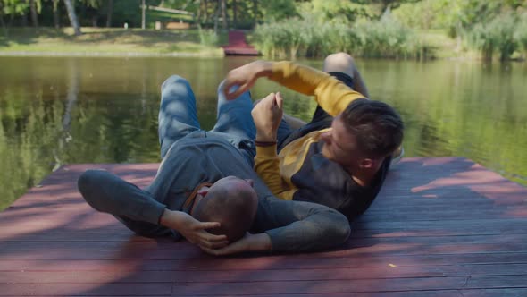 Loving Homosexual Partners Lying on Pier By Pond