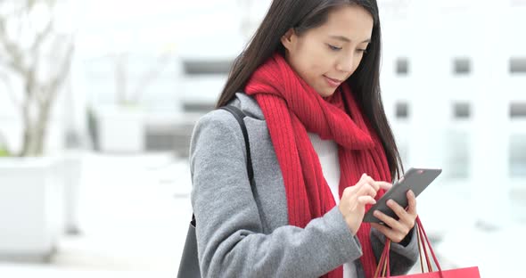 Woman use of smart phone and holding shopping bag