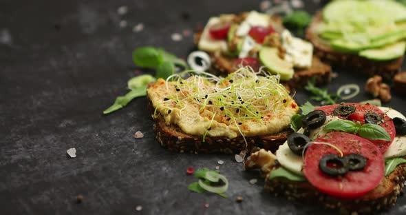 Variety of Healthy Fresh Sandwiches with Different Vegetables, Herbs and Ingredients on Dark Table