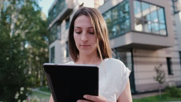 Young Business Woman Who Works on the Internet on a Tablet Outdoors