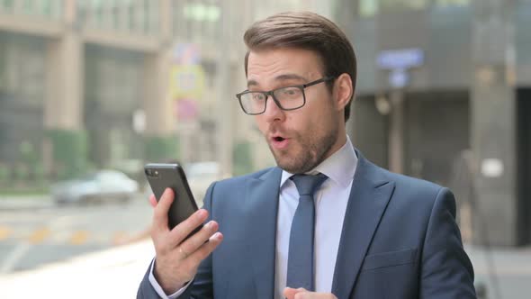Portrait of Businessman Celebrating on Smartphone, Outdoor