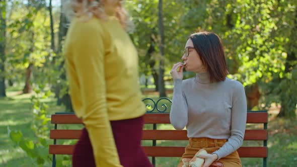 Young Happy Woman Eating Baguette in City Park