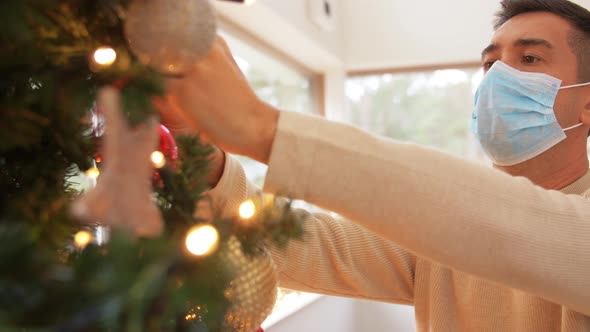 Man in Mask Decorating Christmas Tree at Home