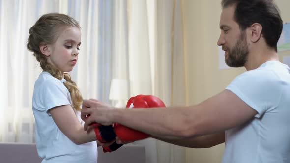 Sport Father Helping Daughter Put on Boxing Gloves, Home Training, Self-Defense