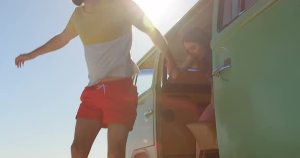 Happy young couple holding hands and getting out from the van 4k