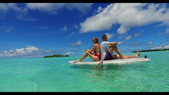 Young couple posing on idyllic lagoon beach holiday by clear lagoon with white sand background of th